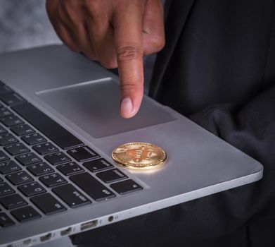 hand pointing golden bitcoin with a laptop computer 
