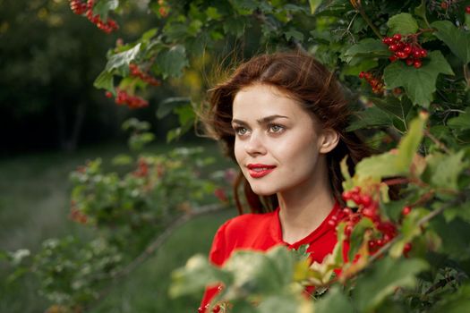 cheerful woman in a red shirt bush berries countryside. High quality photo