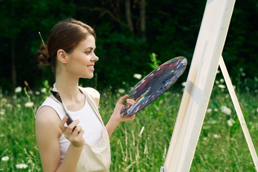 cheerful woman paints a picture palette nature landscape. High quality photo