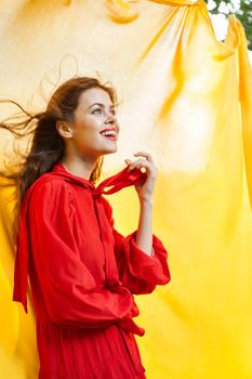 smiling woman in red dress posing yellow background. High quality photo