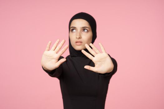 cheerful muslim woman black hijab posing hand gesture pink background. High quality photo