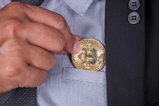 close up business man in suit pick bitcoin in to pocket