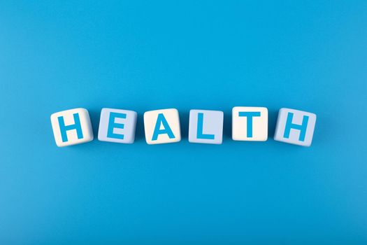 Health single word written on white and blue cubes in a row on dark blue background. Concept of mental and physical health, medications, life insurance or wellbeing