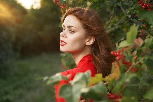 pretty woman in red dress green leaves berries nature summer. High quality photo