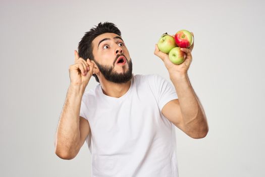 Cheerful man with apples in his hands in a white t-shirt fruits. High quality photo