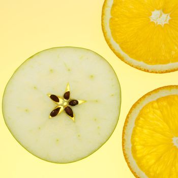 three orange and apple slices on yellow background