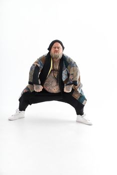 Fat stylish bearded tattoed caucasian man with big belly is posing and dancing wearing ethnic kimono