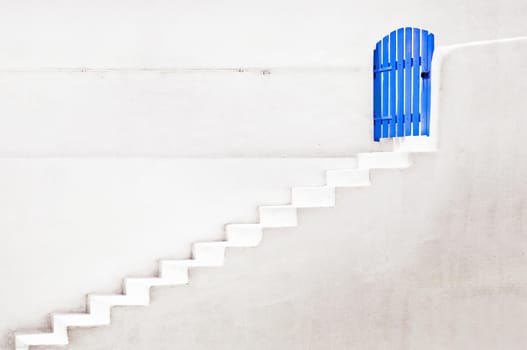 Concept of a blue door with a white wall and stairs down the door, concept of doors and stairs