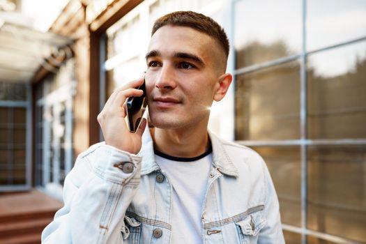 Young casual man walking on the city street and talking on the phone, close up portrait