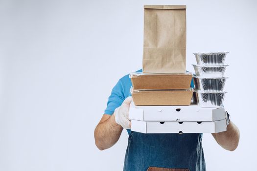 Unrecognizable man in blue polo shirt with food delivery orders against light grey background