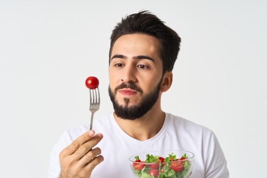 cheerful man in a white t-shirt a plate with salad vegetables diet. High quality photo