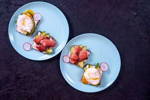 Bread Toasts with Cream Cheese, Avocado, Poached Egg and Salmon Fish on Dark Background. Healthy Breakfast or Appetizer Concept. Copy Space.