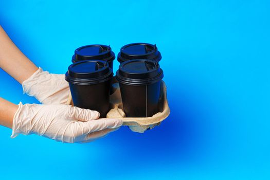Coffee delivery. Human hand holding takeaway coffee cup on paper background
