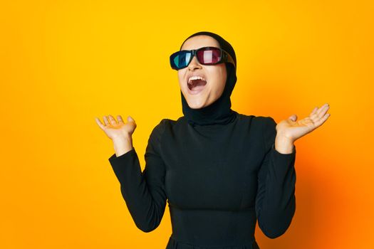 Muslim in black hijab popcorn 3D glasses cinema yellow background. High quality photo