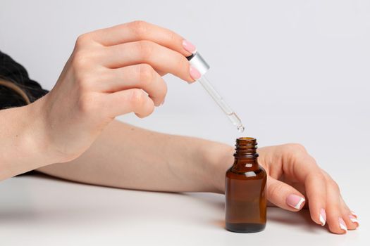 Female hand applying skincare product with pipette close up