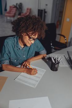 Top view of smiling Afro American woman working with document and sitting at workplace in the office