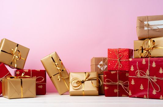 Pile of stacked gift boxes against pink background front view