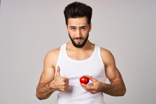 a man in a white t-shirt fresh tomatoes healthy lifestyle diet food studio lifestyle. High quality photo