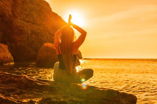 Young woman in swimsuit with long hair practicing stretching outdoors on yoga mat by the sea on a sunny day. Women's yoga fitness pilates routine. Healthy lifestyle, harmony and meditation concept.