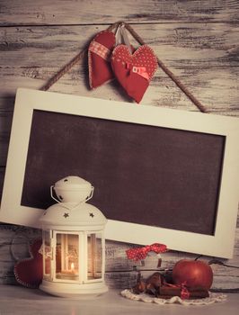 Cristmas lantern with board for greetings over shabby wooden wall