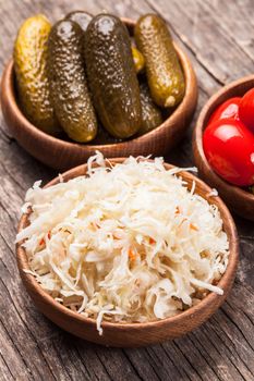 Sauerkraut and pickled cucumbers and tomatoes in wooden bowls