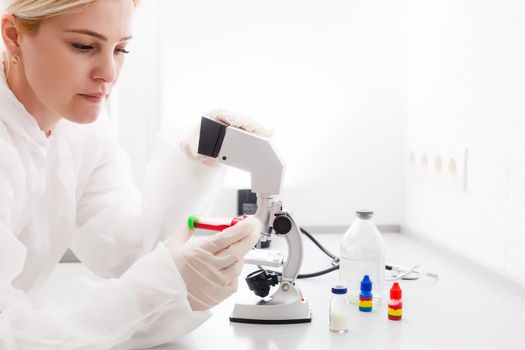 A beautiful female medical or scientific researcher using her microscope in a laboratory.