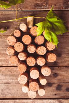Wine corks on wooden backgroud as a grape shape with green leaf