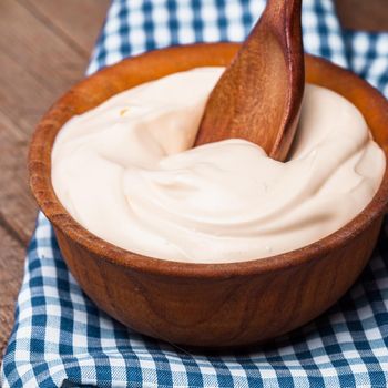 Sour cream in a wooden bowl. Farm organic product