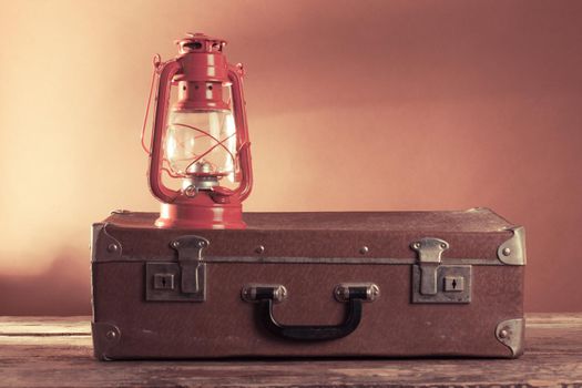 Old vintage suitcase and kerosene lamp on a woode floor