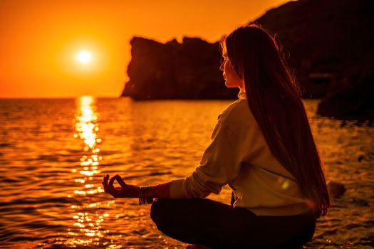 Young woman in swimsuit with long hair practicing stretching outdoors on yoga mat by the sea on a sunny day. Women's yoga fitness pilates routine. Healthy lifestyle, harmony and meditation concept.