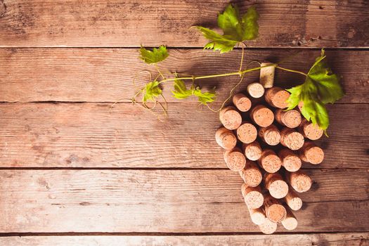 Wine corks on wooden backgroud as a grape shape with green leaf