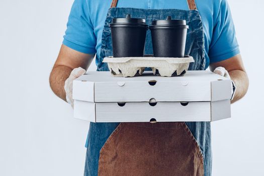 Unrecognizable man in blue polo shirt with food delivery orders against light grey background