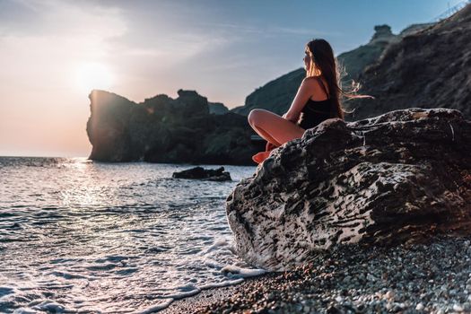 Young woman in swimsuit with long hair practicing stretching outdoors on yoga mat by the sea on a sunny day. Women's yoga fitness pilates routine. Healthy lifestyle, harmony and meditation concept.