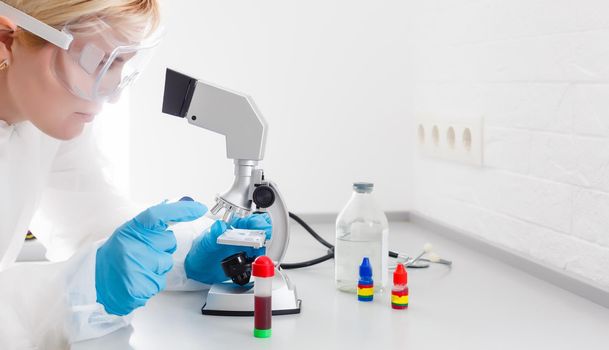 A beautiful female medical or scientific researcher using her microscope in a laboratory.