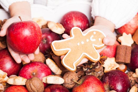 Child's hands hold a red apple and gingerman cookie