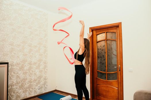 Young woman with long hair, fitness instructor in black sportswear, doing stretching and pilates on yoga mat at home. Female fitness yoga routine concept. Healthy lifestyle harmony and meditation