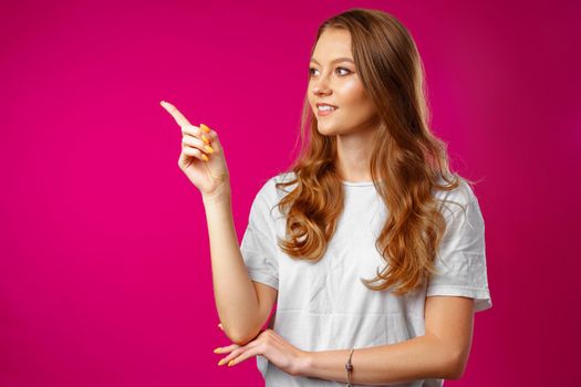 Portrait charming pretty cheerful girl showing copy space with her finger