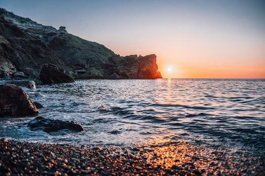 Seascape over the Jasper beach during sunset, with rocky cliff is lit by the warm sunset. Long exposure. motion blurry clouds. Copy space. The concept of calmness silence and unity with nature