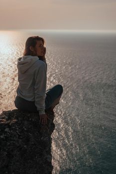 woman traveler drinks coffee with a view of the mountain landscape. A young tourist woman drinks a hot drink from a cup and enjoys the scenery in the mountains. Trekking concept