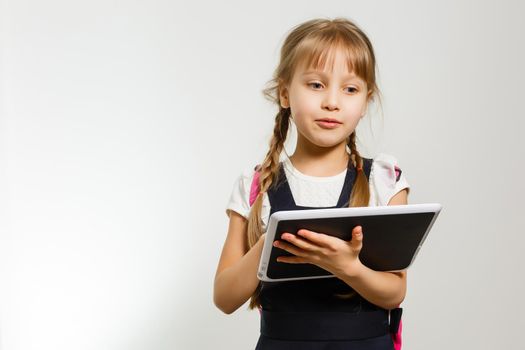 The little girl using the tablet on the white wall background