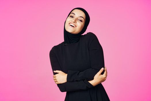 cheerful muslim woman in black hijab posing fashion pink background. High quality photo