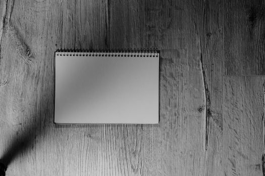 The notebook is located horizontally on a wooden background. Black and white photo.