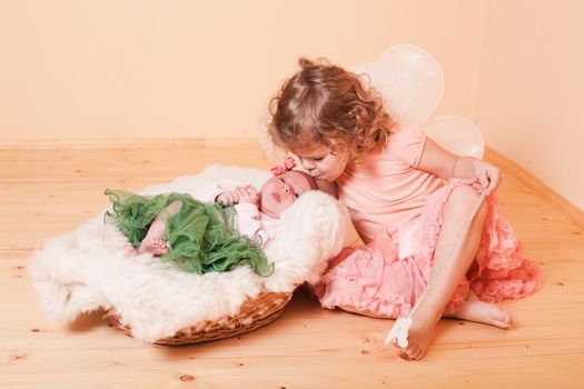 Little girl with her newborn sister in a basket