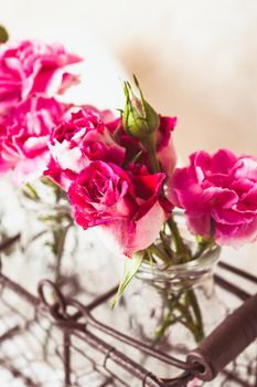 Pink flowers in glass bottles in metal basket. Vintage decor concept