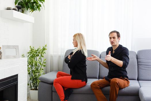 Happy young couple is hugging and smiling while sitting on the couch at the psychotherapist.