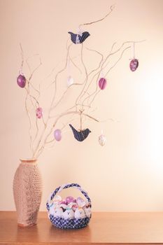 Handmade easter decorations on the branches in vase and textile basket