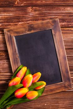 Tulips with chalkboard on a wooden background - spring greetings