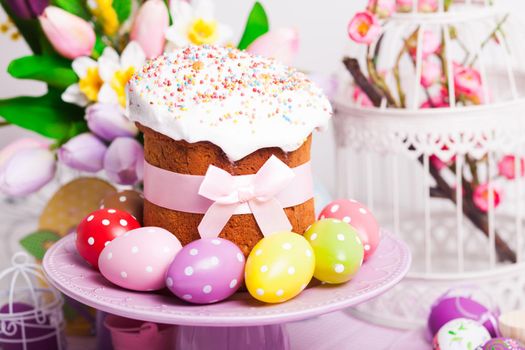 Easter cake and colorful polka dot eggs on the plate and flowers on the foreground