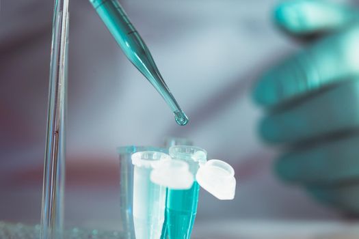 Scientist holds pipette and drops into eppendorf tube