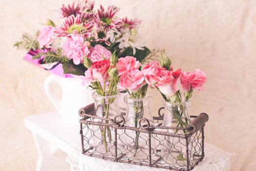 Pink flowers in glass bottles in metal basket. Vintage decor concept